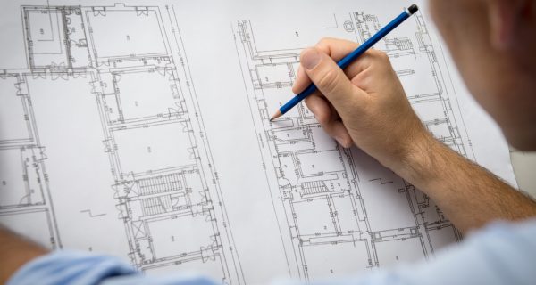 Closeup Of Male Architect Working On Blueprint At Office.